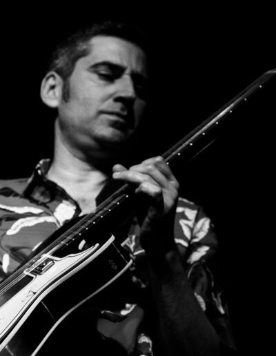 Guitarrista de jazz con guitarra de caja y camisa estampada, ojos cerrados, blanco y negro