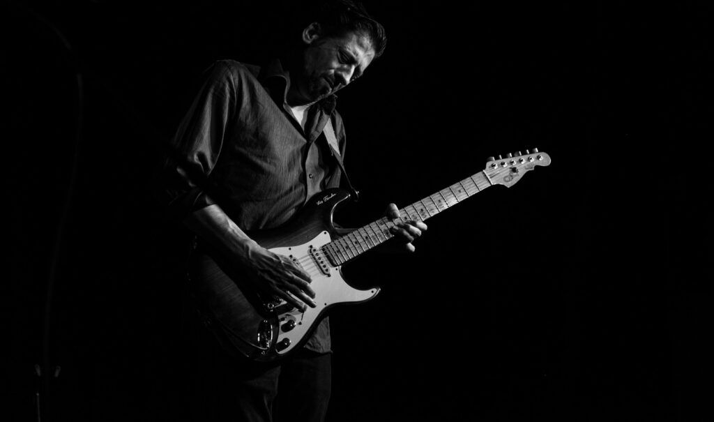 Guitarrista tocando una Fender Stratocaster en directo, fotografía en blanco y negro