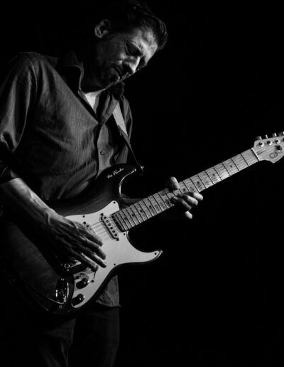 Guitarrista tocando una Fender Stratocaster en directo, fotografía en blanco y negro