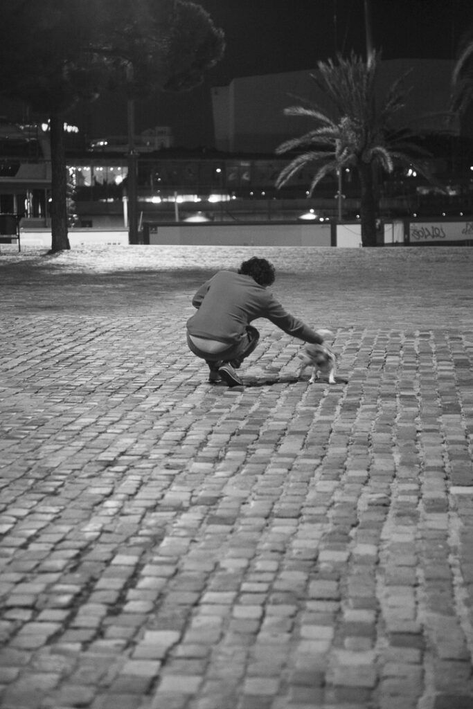 Chica paseando con su perro en la ciudad, fotografía callejera en blanco y negro de Lluís Ridao