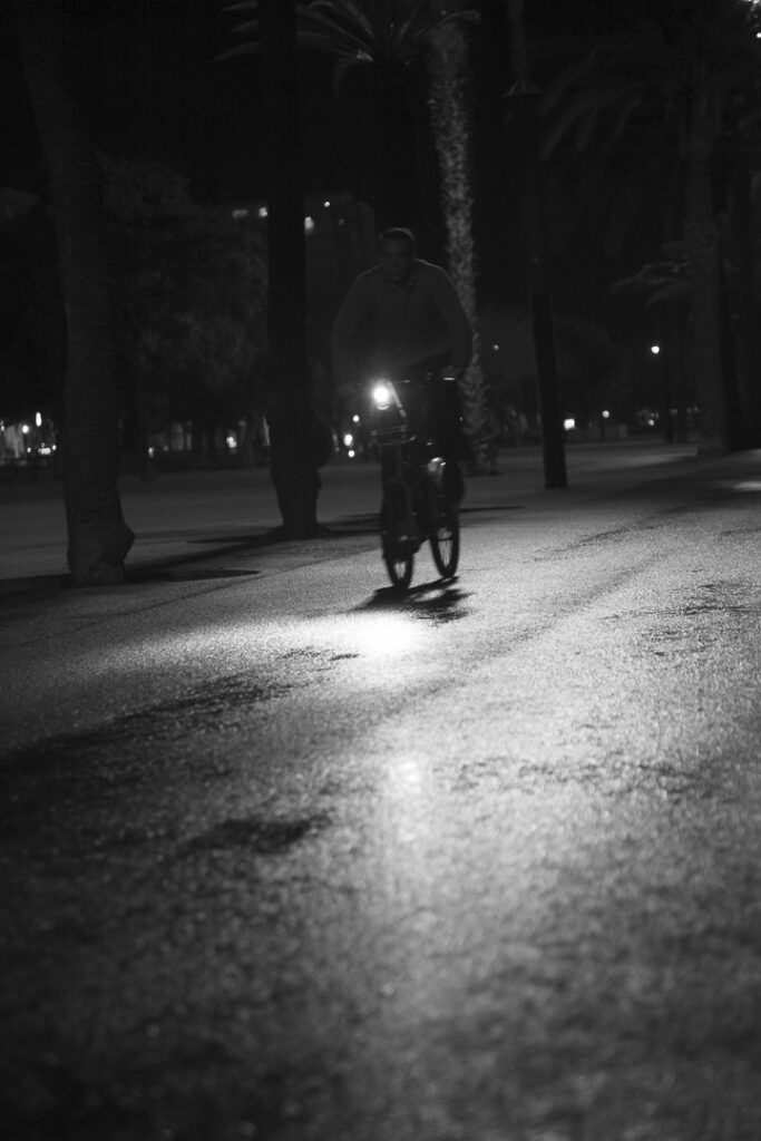 Ciclista de noche en un paseo de la Barceloneta, en blanco y negro
