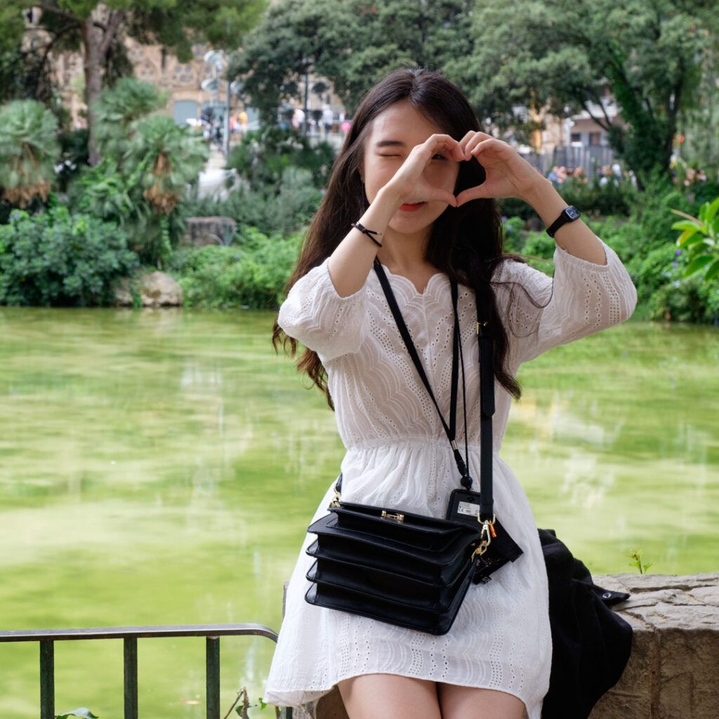 Mujer joven sonriente con las manos en el rostro en un parque