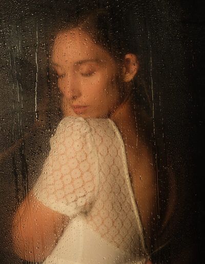 Retrato de estudio de una mujer joven con vestido blanco y la mirada baja, luz suave