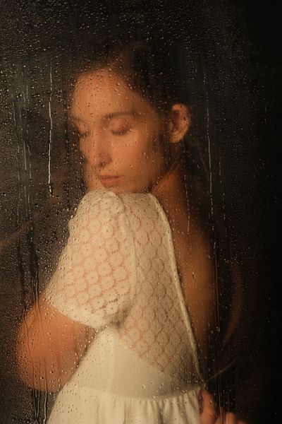 Retrato de estudio de una mujer joven con vestido blanco y la mirada baja, luz suave