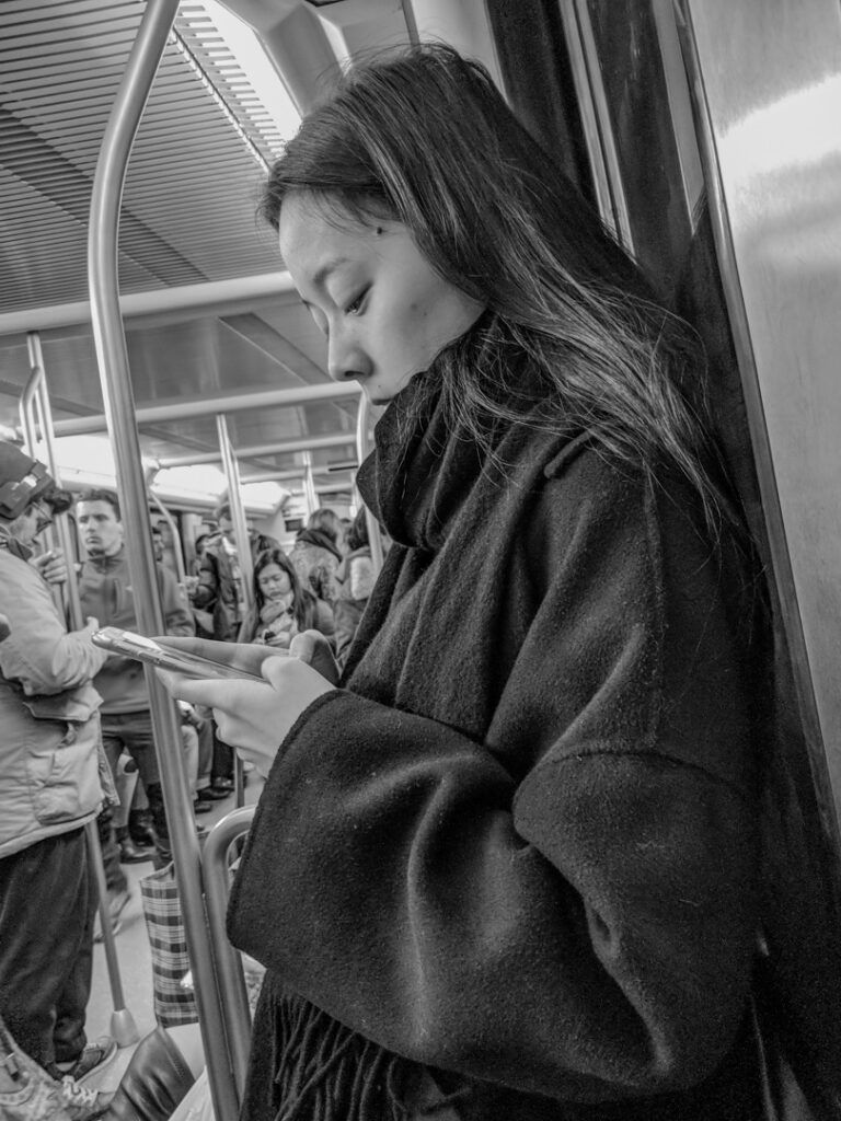Persona mirando likes en redes sociales en el metro, fotografía callejera de Lluís Ridao
