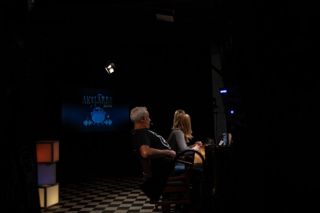 Dos participantes del podcast sentados en penumbra durante la grabación