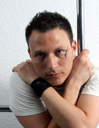 Retrato de estudio de un hombre con camiseta blanca posando con las manos junto a los hombros