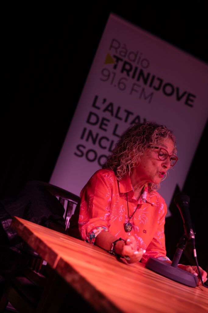 Mujer con gafas y camisa roja hablando al micrófono en Ràdio Trinijove