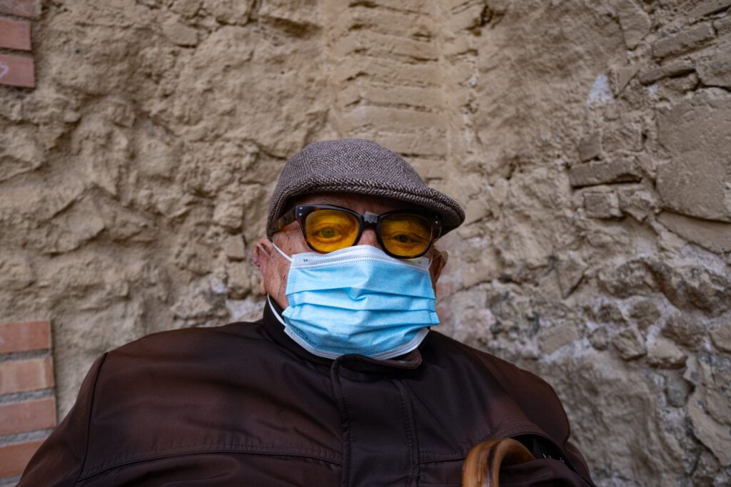 Hombre con gorra, gafas y mascarilla en la calle durante la pandemia