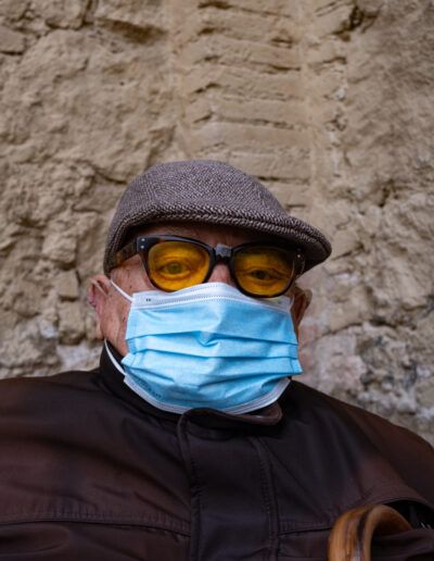 Hombre con gorra, gafas y mascarilla en la calle durante la pandemia