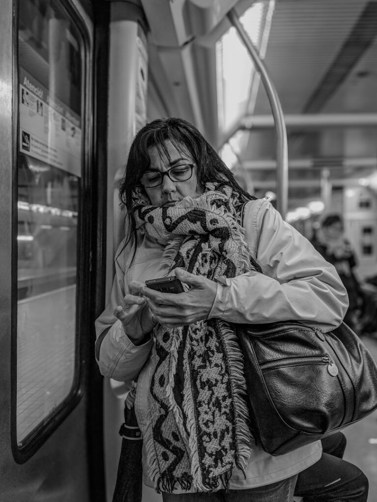 Persona respondiendo correos electrónicos en el teléfono en el metro, fotografía callejera de Lluís Ridao