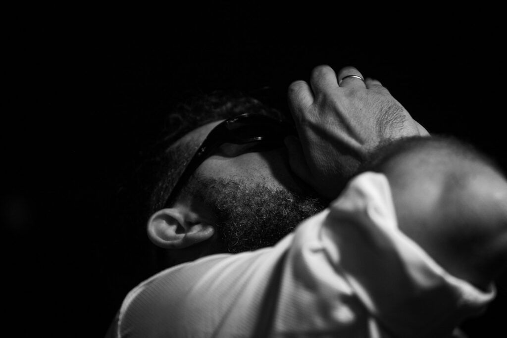 Retrato cercano de un hombre con gafas de sol y la mano en la cabeza, blanco y negro