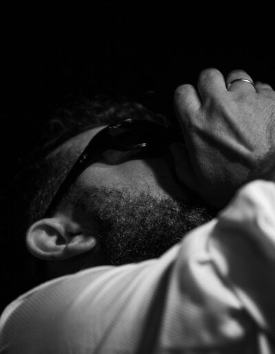 Retrato cercano de un hombre con gafas de sol y la mano en la cabeza, blanco y negro