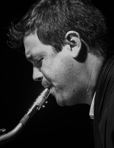 Saxofonista de jazz de perfil tocando el saxo en directo, fotografía en blanco y negro