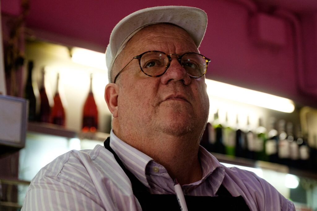 Hombre mayor tras la barra de un bar, retrato de calle