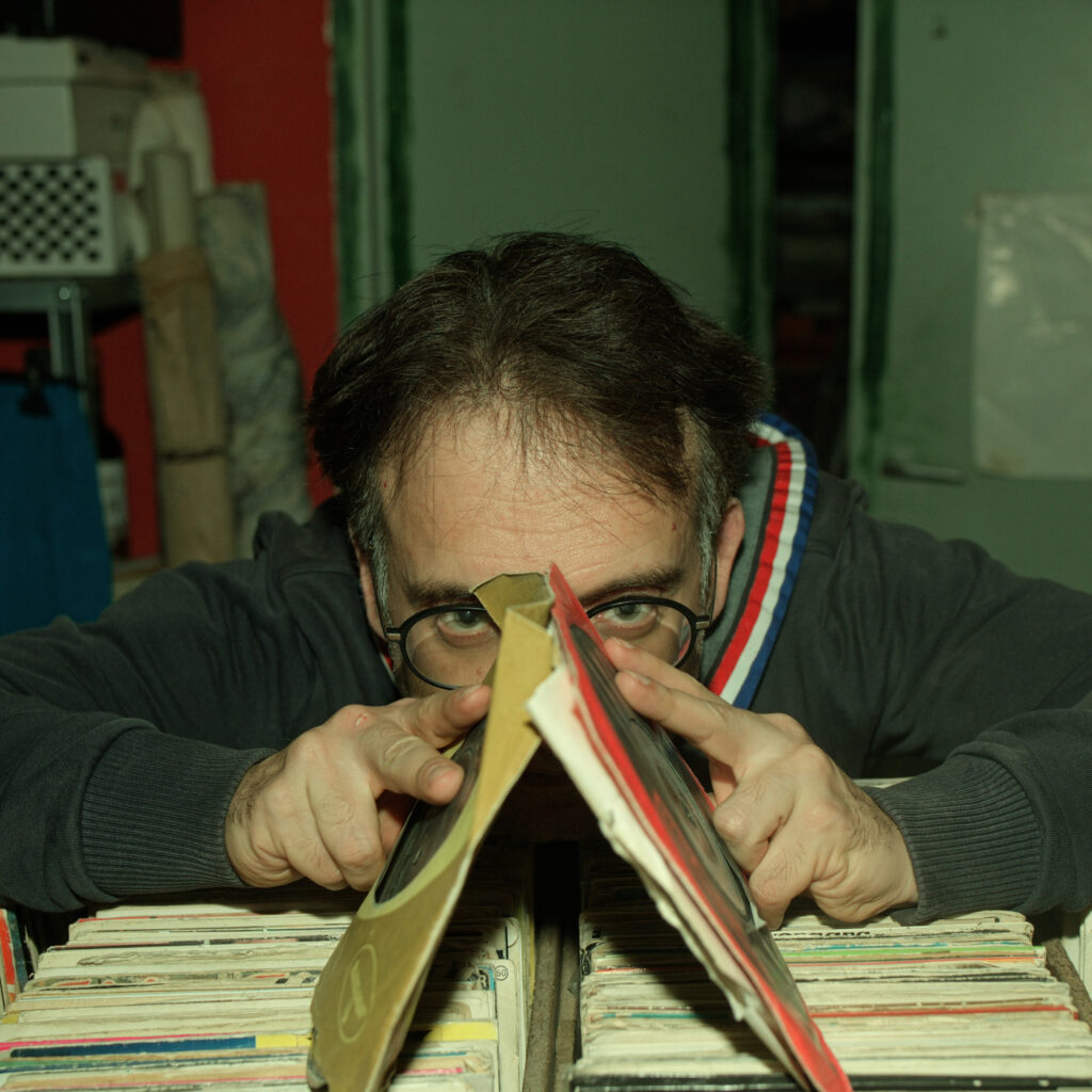 Autorretrato asomado entre discos de vinilo, con gafas y la mirada por encima de las fundas