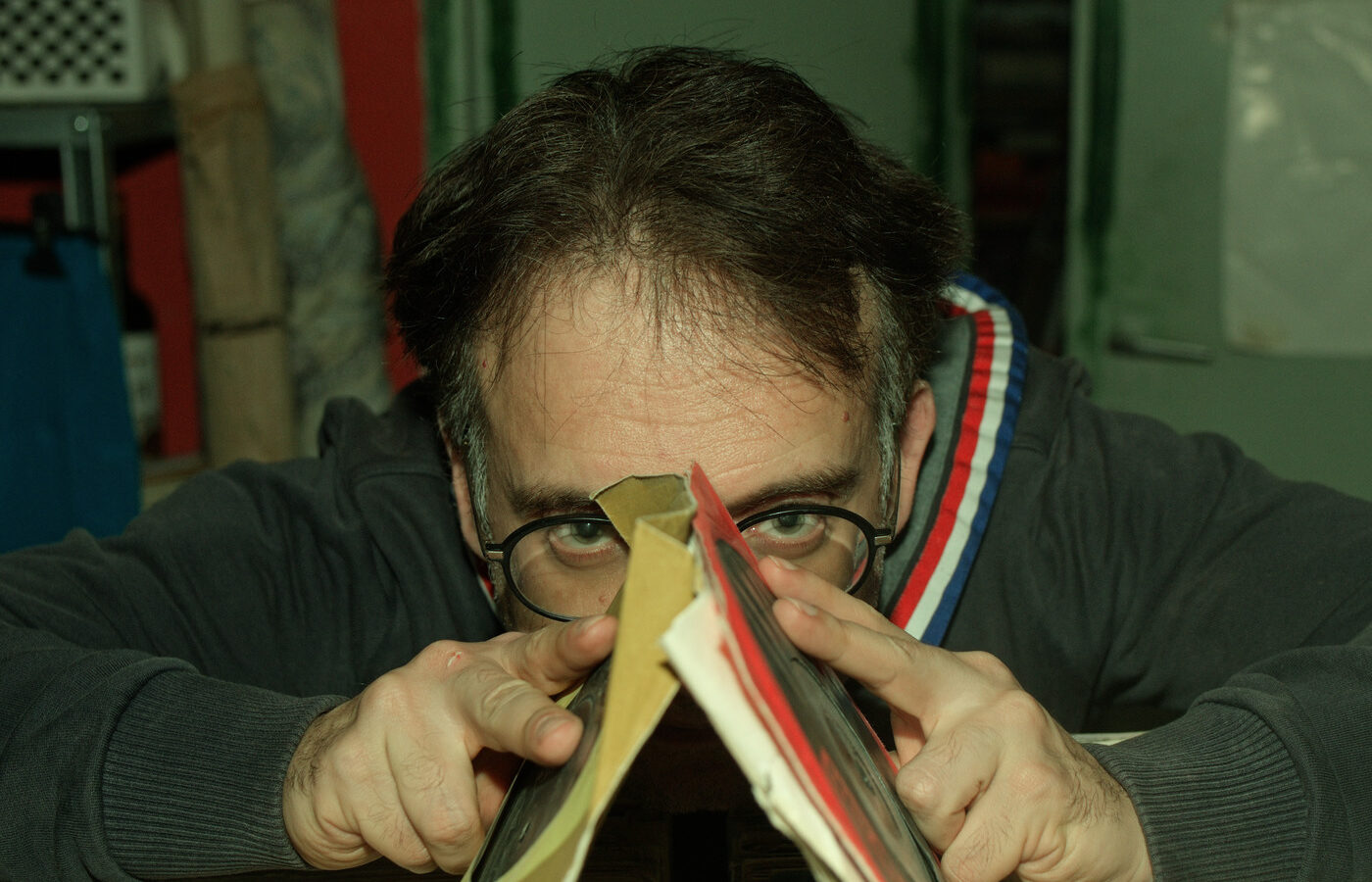 Autorretrato asomado entre discos de vinilo, con gafas y la mirada por encima de las fundas