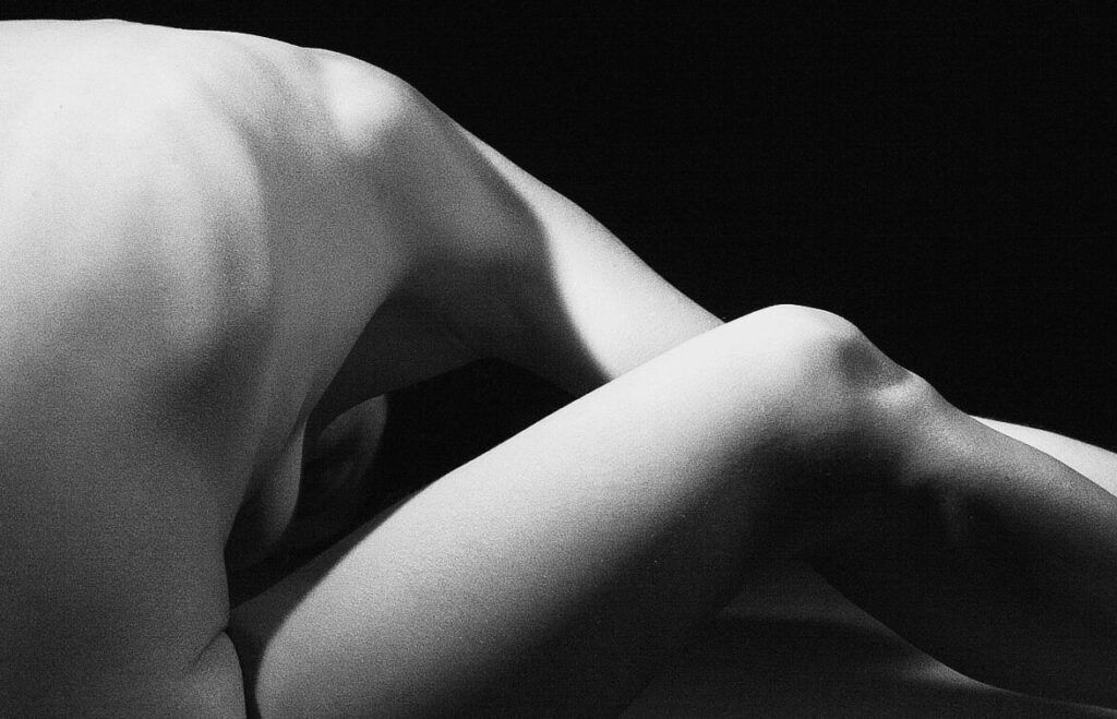 Desnudo artístico en blanco y negro: detalle de espalda y pierna en una postura de yoga