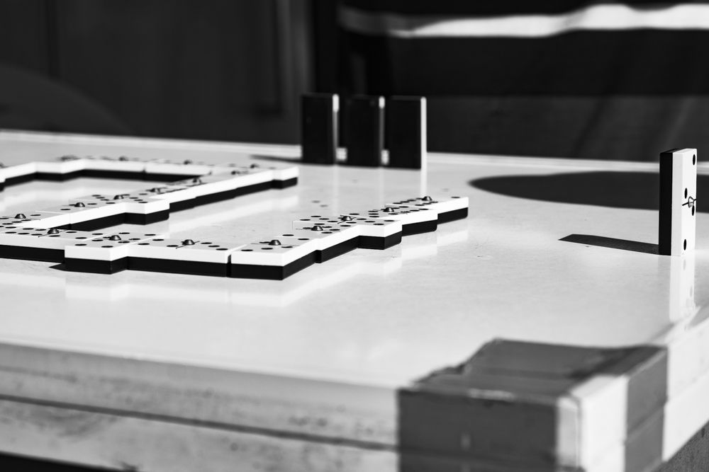 Fichas de dominó alineadas sobre la mesa durante una partida, en blanco y negro