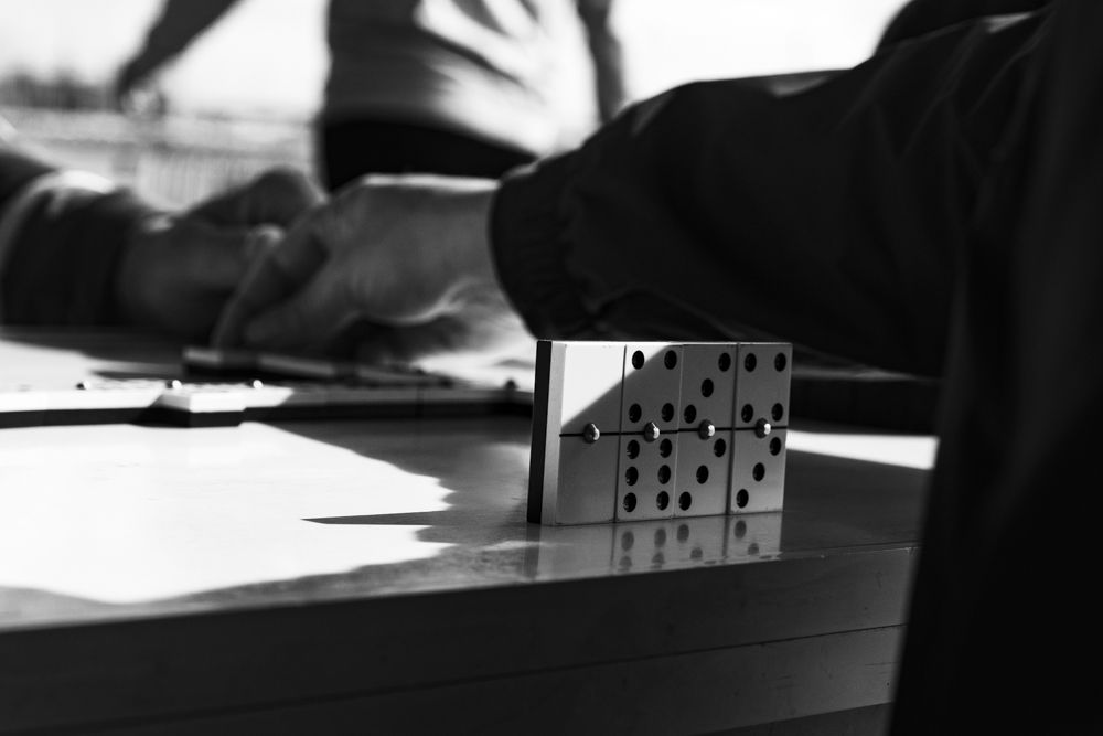 Jugador de dominó con sus fichas de pie sobre la mesa, en blanco y negro